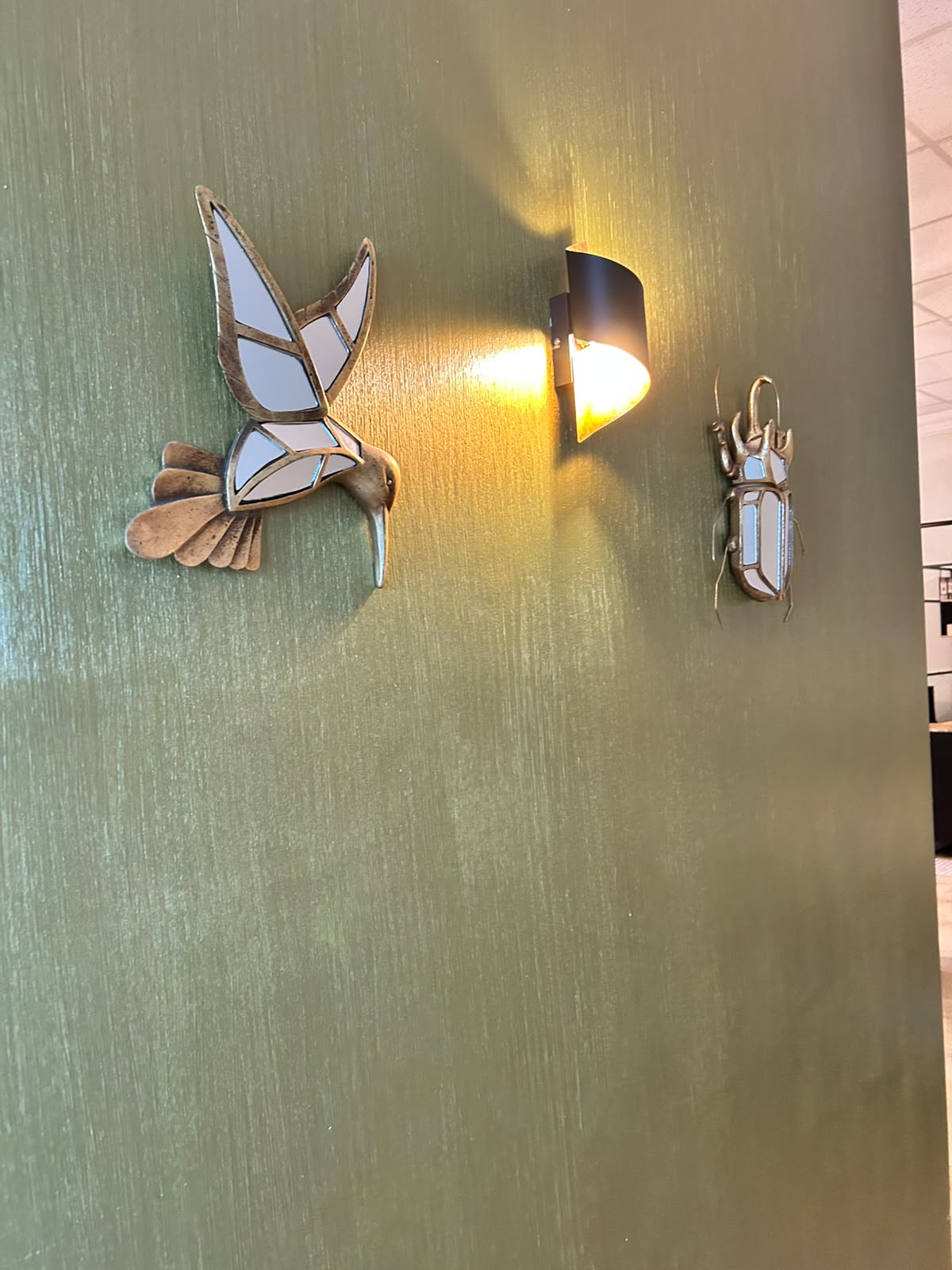 Messing-Wanddekoration und Leuchte auf olivgrüner Wand